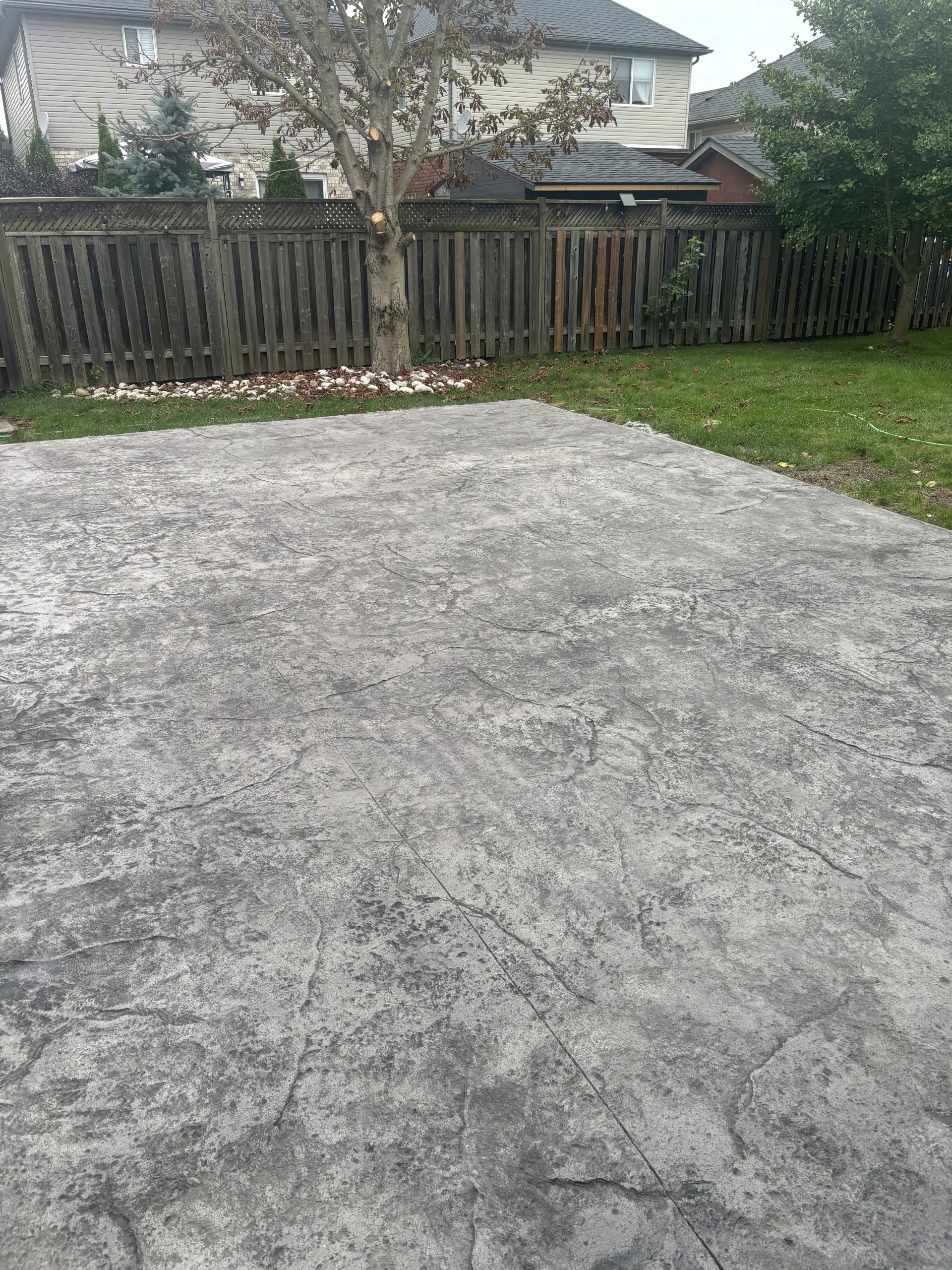 A stamped concrete patio in a backyard by Ultimate Touch Concrete, a concrete company in London Ontario specializing in both residential and commercial concrete services.