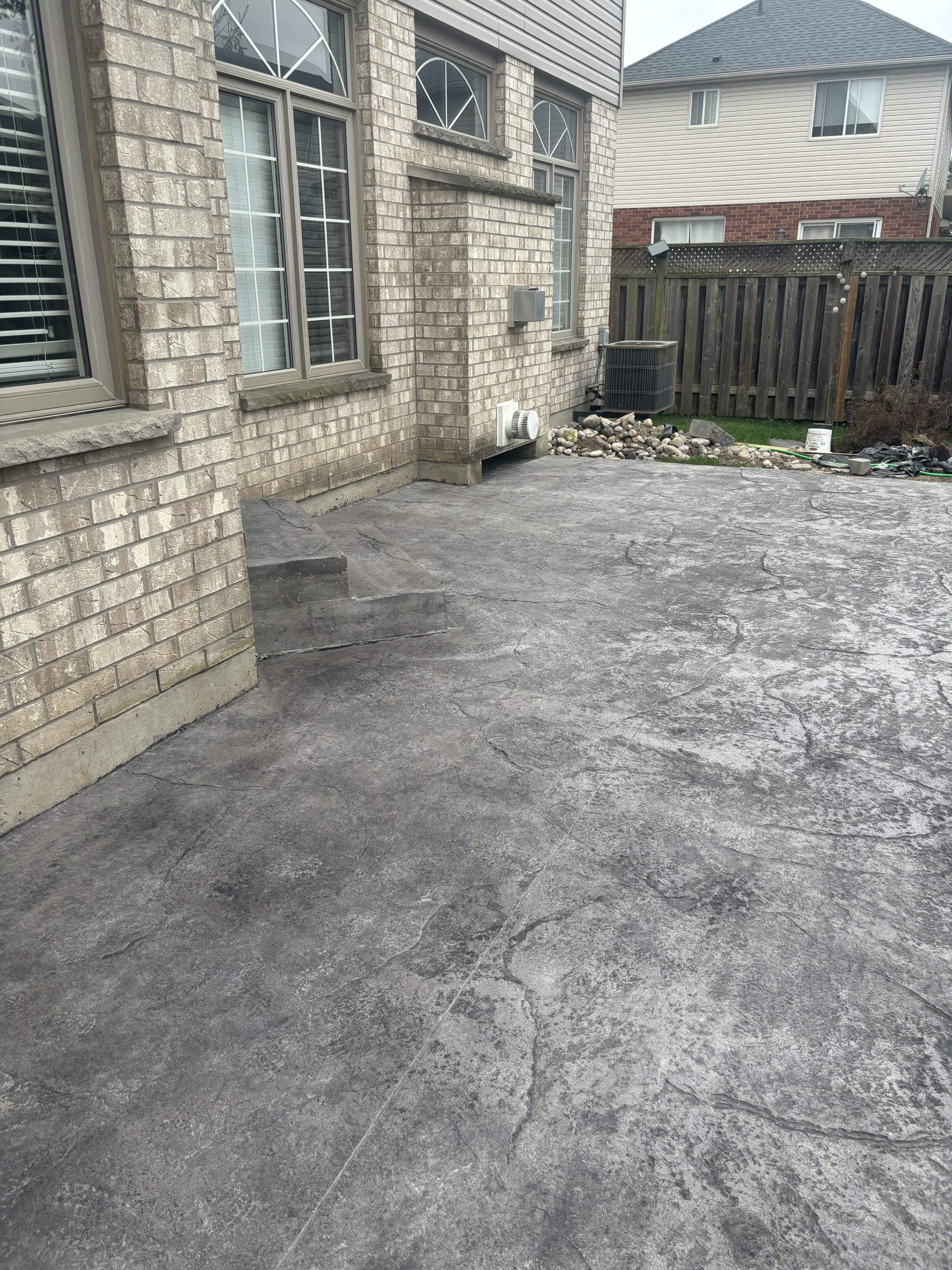 A stamped concrete patio in a backyard by Ultimate Touch Concrete, a concrete company in London Ontario specializing in both residential and commercial concrete services.
